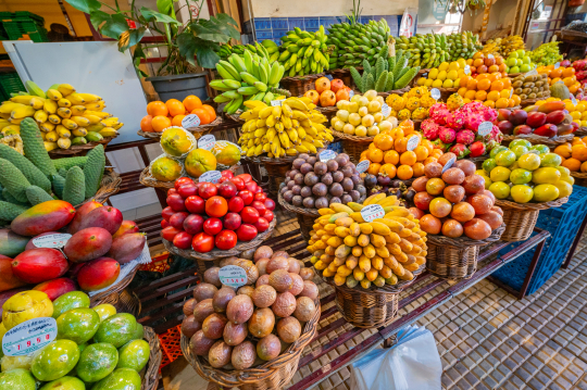 Marktstand mit unzähligen Obstkörben voll mit frischen, bunten Obst in der Markthalle von Funchal