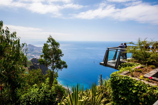 Blick von der Seite auf den berühmten Skywalk auf Madeira, zwei Personen von der Seite zu sehen und ein weiter Blick über die Küste